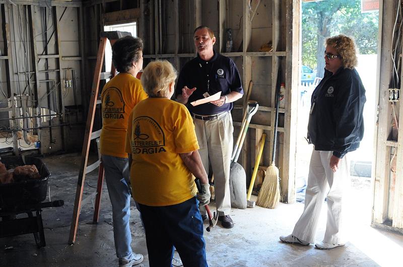 Relief personnel and volunteers conducting indoor flood cleanup and gutting of water-damaged property